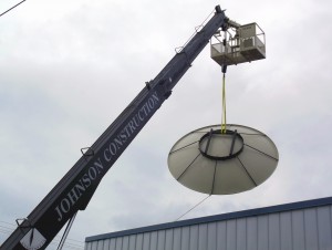 A crane hoists the new satellite to the roof.