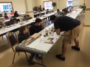 Ron Fairbanks teaching kids how to paint formline. (Aaron Bolton, KSTK News)