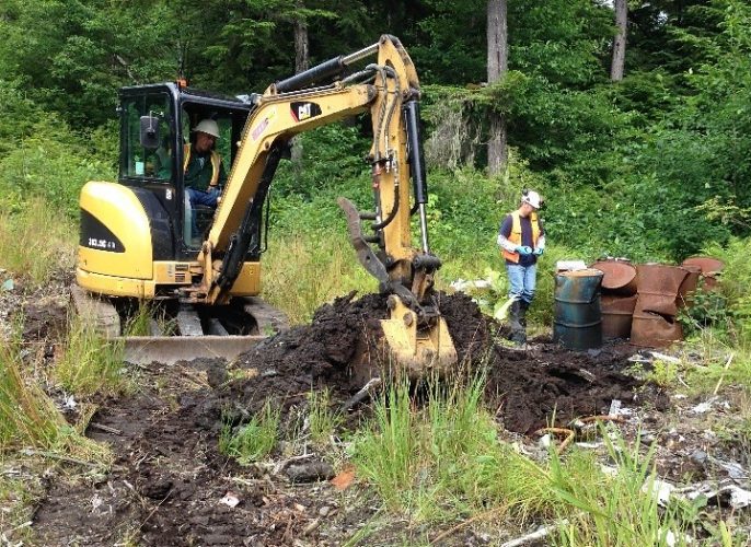 A backhoe digs up part of the old Byford Junkyard in Wrangell. After removing old cars, oil drums and other trash, the state is treating and moving contaminated soil to a rock quarry south of town. (Photo courtesy Department of Environmental Conservation)